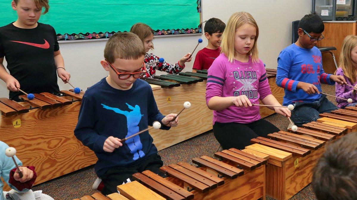 Students play wooden xylophones