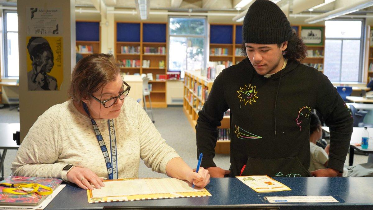 student talking with teacher in media center